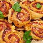 Girelle di pasta sfoglia pronta e prosciutto in un vassoio