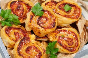 Girelle di pasta sfoglia pronta e prosciutto in un vassoio