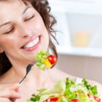Una donna allegra che mangia delle verdure