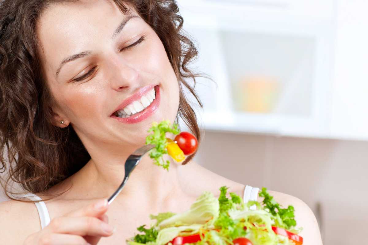 Una donna allegra che mangia delle verdure