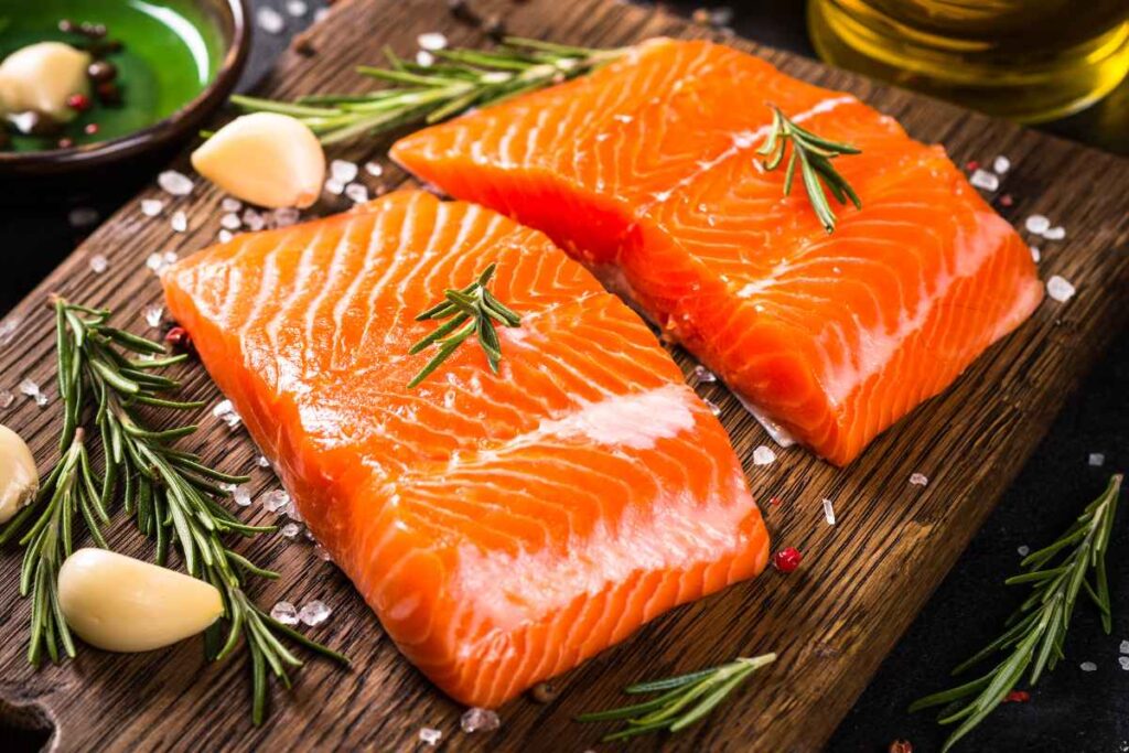 Filetti di salmone su tagliere di legno con spezie