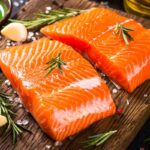 Filetti di salmone su tagliere di legno con spezie