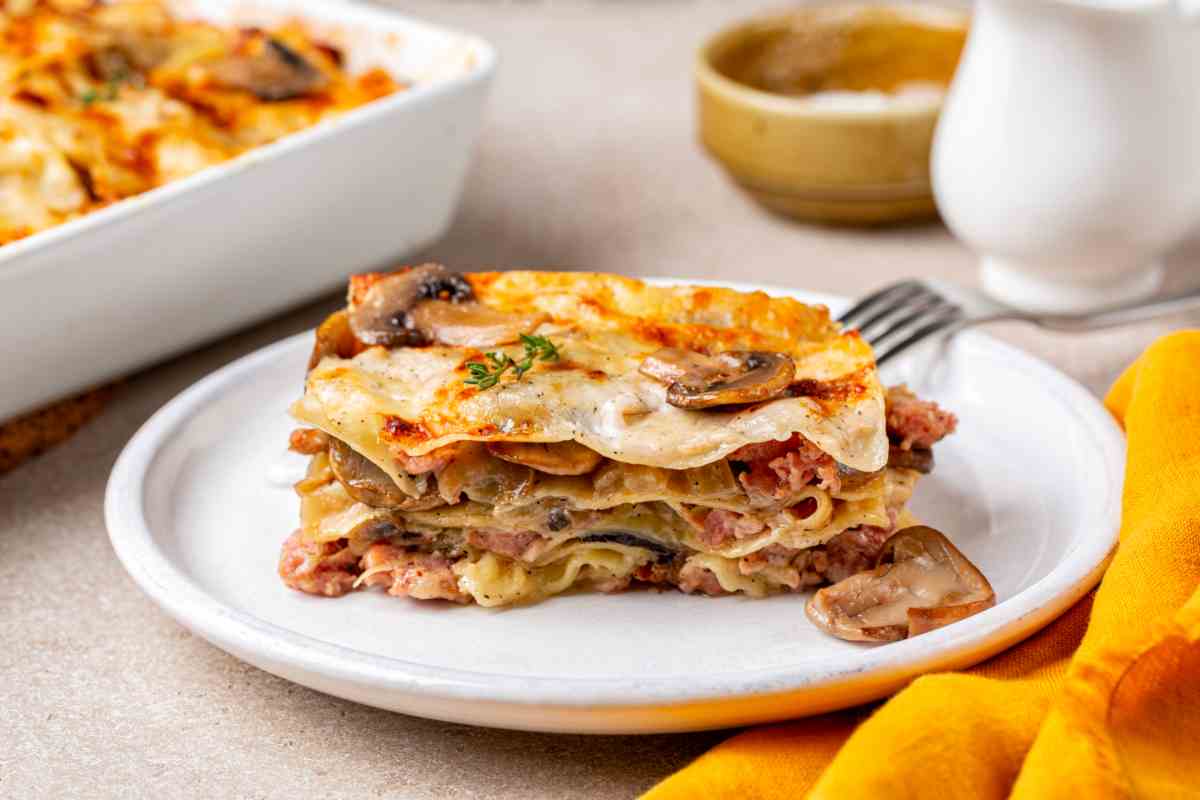 tavola apparecchiata con un piatto di lasagne ai funghi porcini e salsiccia