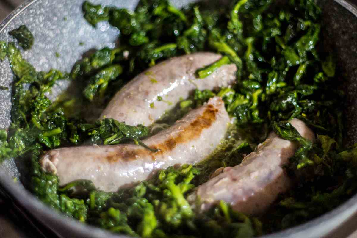 una padella in cui dentro cuociono salsicce e friarielli